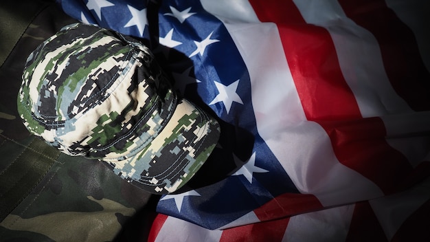 Foto sombrero militar o bolsa con bandera americana. sombrero de soldado o casco con bandera nacional americana sobre fondo negro. represente el concepto militar con un objeto de camuflaje y la bandera de la nación de ee. uu.