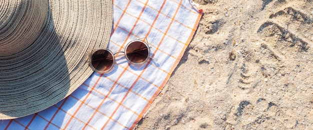 Sombrero de mujer, gafas en la playa. Vista superior, endecha plana. Bandera.