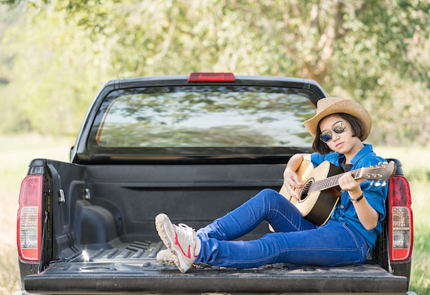 Foto sombrero de mujer y tocando la guitarra en camioneta