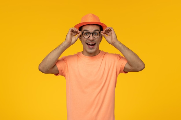 Sombrero naranja lindo joven en camiseta naranja con el sombrero con gafas y riendo