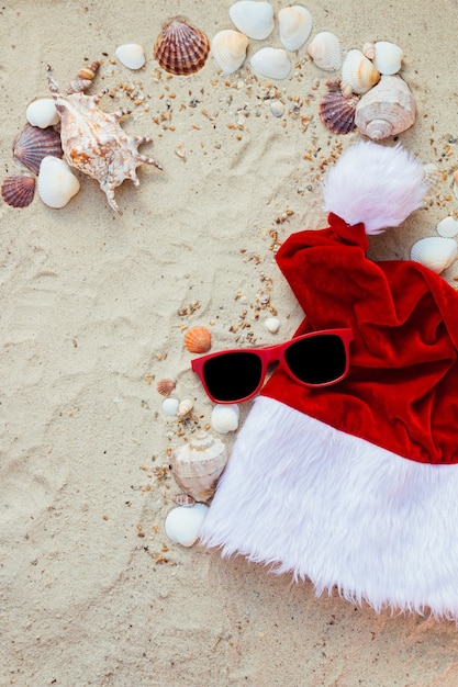 Sombrero de Navidad y gafas de sol rojas en la playa.