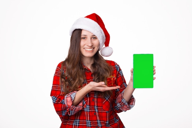 Sombrero de Navidad de mujer joven apuntando en tableta con pantalla vacía en blanco