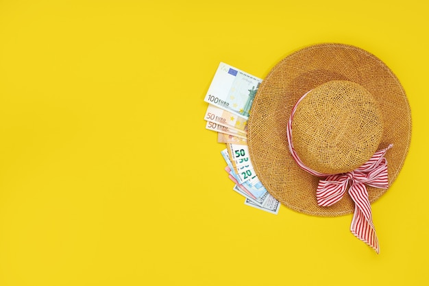 Sombrero de paja con billetes de euro aislado sobre un fondo amarillo