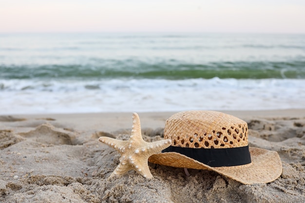 Sombrero de paja y estrellas de mar en la hermosa arena junto al mar