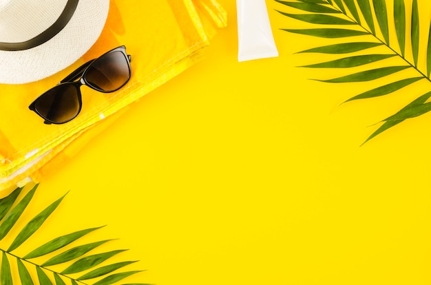 Sombrero de paja con gafas de sol y hojas de palmera.