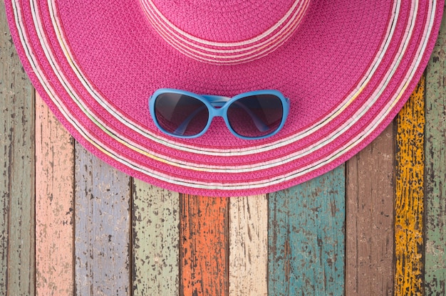 Foto sombrero de paja y gafas de sol en madera de época.