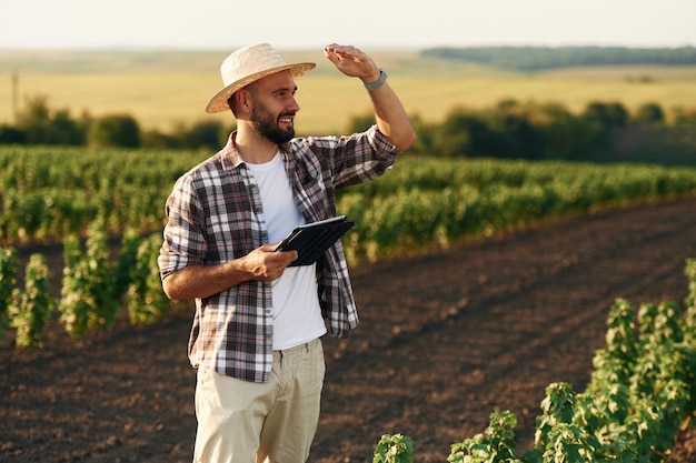 En el sombrero de paja el granjero está en el campo agrícola