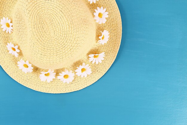 Sombrero de paja con la manzanilla en un fondo azul. Vista superior. Fondo de verano Lay Flat.