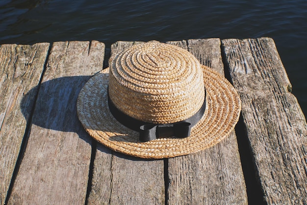 Sombrero de paja en el muelle de madera Foto rústica y natural al aire libre Río de verano Concepto de relajación y viajes Wanderlust Turistas senderismo