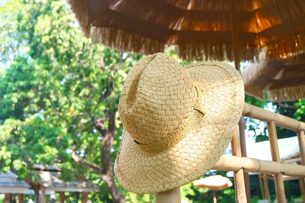 Sombrero de paja bajo la sombrilla de playa para el concepto de VACACIONES EN LA PLAYA