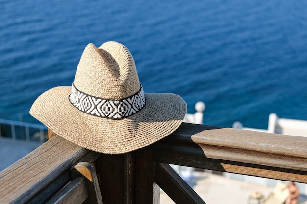 sombrero de paja en la terraza de madera con vistas al mar y a la piscina