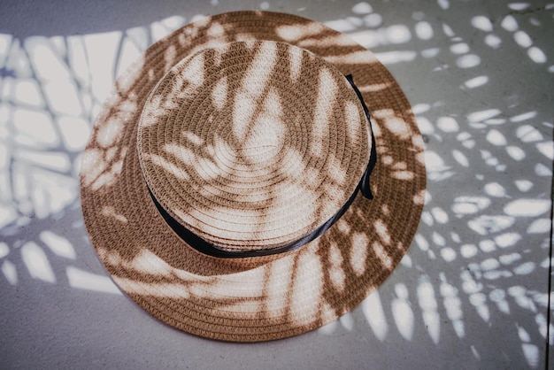 Sombrero de paja de verano a través de las sombras de las ramas de las palmeras