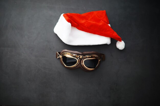 Sombrero de Papá Noel, gafas y nariz con mascarilla sobre fondo rojo. Concepto de celebración de Navidad o año nuevo. Reno navideño elaborado con mascarilla protectora y adornos. Concepto de salud.