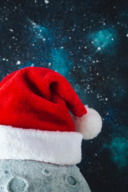 Sombrero de Papá Noel en la luna contra el fondo del cielo estrellado de la noche