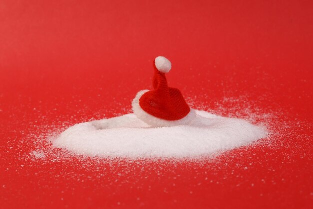 Foto sombrero de papá noel en una nieve de fondo rojo diseño navideño