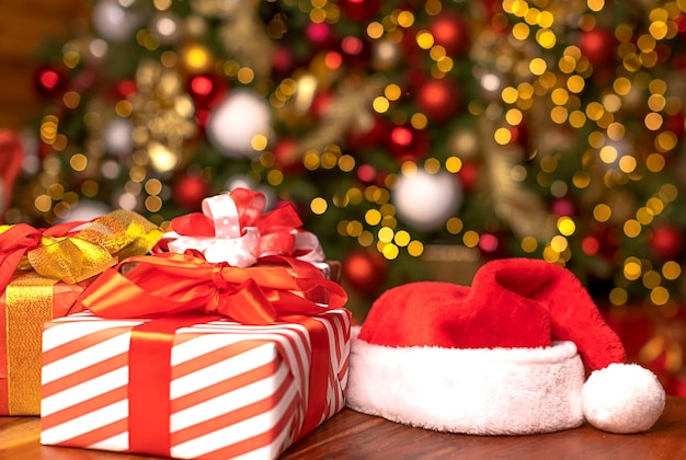 Foto sombrero de papá noel y regalos de navidad en el fondo de un hermoso árbol de navidad decorado con desenfoque de fondo tienda de compras concepto de navidad y año nuevo