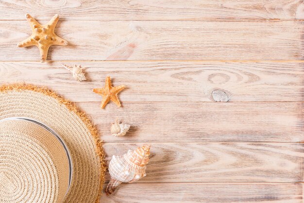 Sombrero de playa con conchas en la mesa de madera marrón. concepto de fondo de verano con vista superior del espacio de copia.