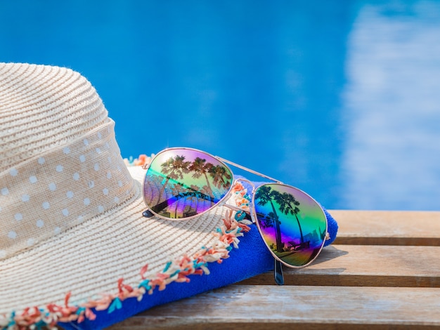 Sombrero de playa con gafas de sol en el lado de la piscina para el concepto de verano