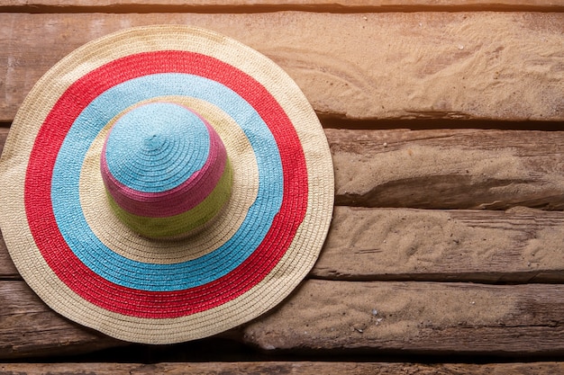Foto sombrero de playa a rayas. sombrero sobre fondo de arena. sombreros de verano para mujer. escóndete del sol.