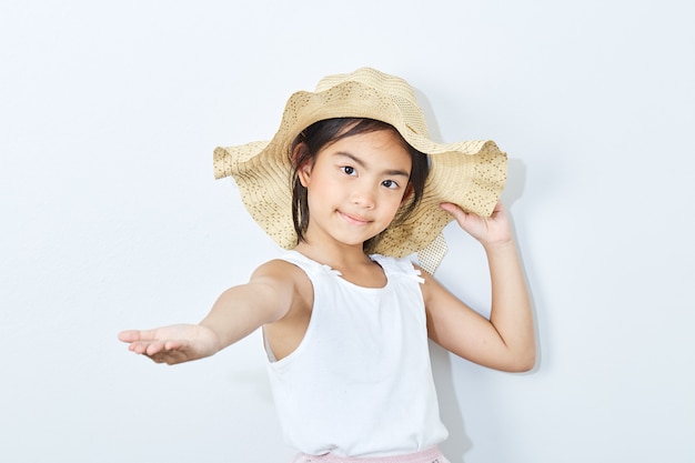 Sombrero que lleva de la muchacha delgada asiática en el fondo blanco.