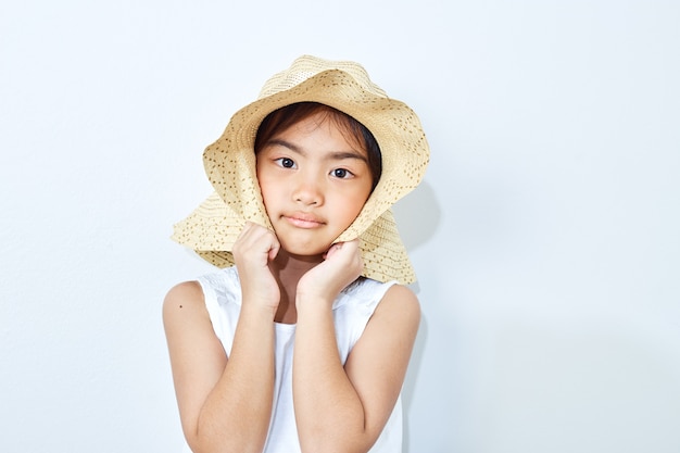 Sombrero que lleva de la muchacha delgada asiática en el fondo blanco.