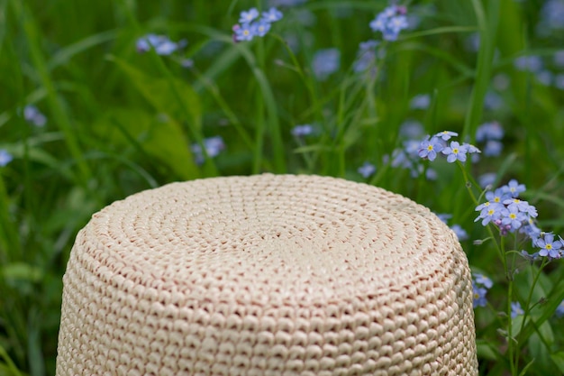 sombrero de rafia natural de verano en la hierba con flores azules no me olvides