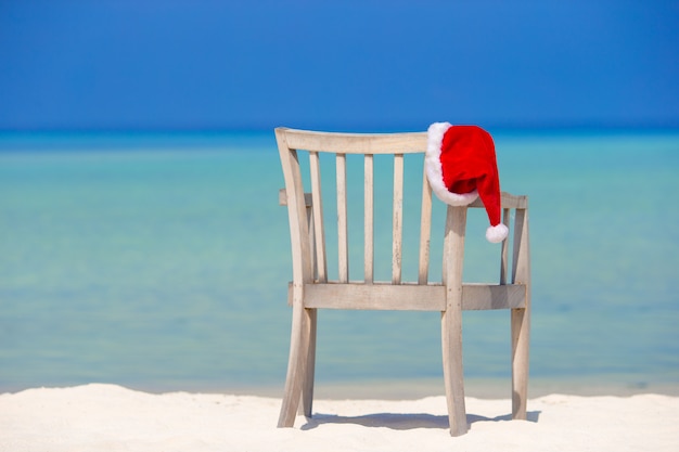 Foto sombrero rojo de santa en silla de playa en vacaciones tropicales