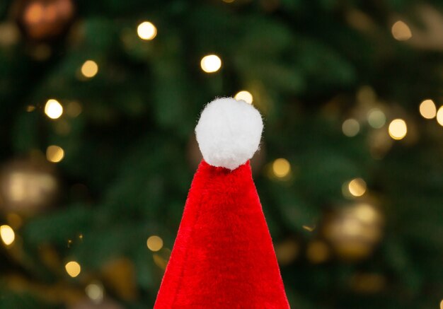 Sombrero de Santa en el fondo de un árbol de Navidad y guirnaldas.