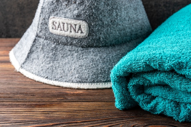 Sombrero de sauna y toalla sobre tabla de madera