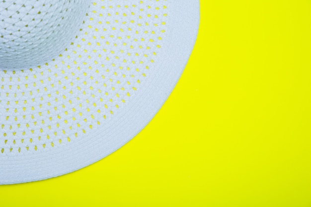 Un sombrero para el sol blanco con ala ancha se encuentra sobre un fondo amarillo con un lugar para el texto