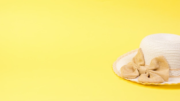 Sombrero para el sol de mujer con un lazo sobre un fondo amarillo brillante