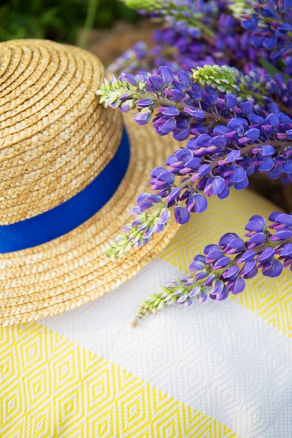Un sombrero, una tela escocesa y un ramo de lupinos en una cesta, primer plano.