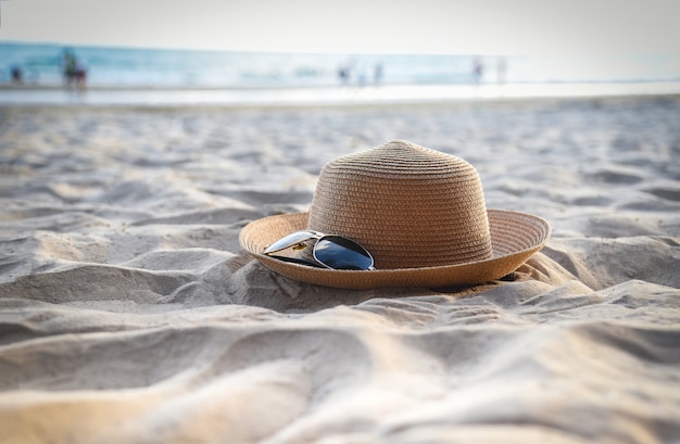 Sombrero de verano: accesorios de gafas de sol y accesorios para gafas de sol sobre un fondo de mar de playa arenosa