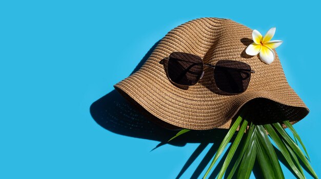 Sombrero de verano con gafas de sol sobre fondo azul Disfrute del concepto de vacaciones Copiar espacio