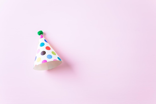 Sombreros de fiesta coloridos para la fiesta de cumpleaños de los niños sobre fondo rosa.