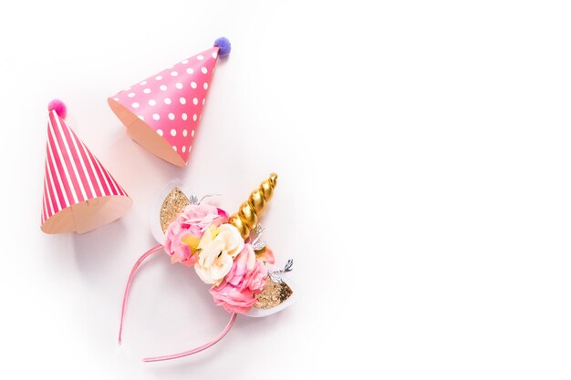 Sombreros de fiesta y diadema de unicornio sobre un fondo blanco.