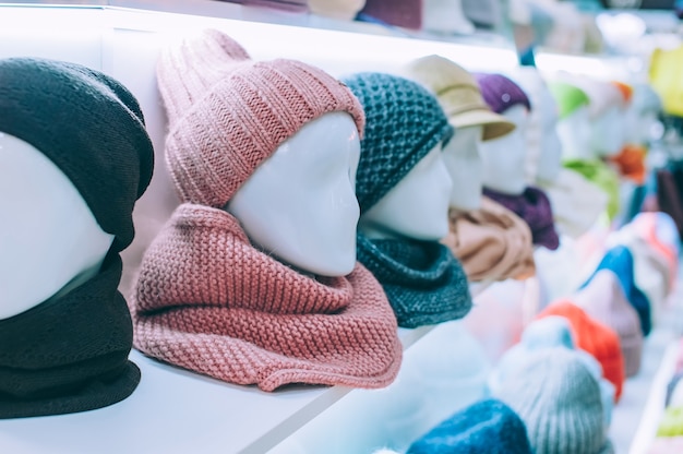 Sombreros de invierno brillantes modernos, con pañuelos en la cabeza de maniquíes en una vitrina de supermercado.