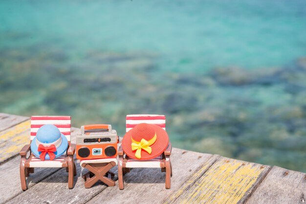 Sombreros miniatura en silla de playa con el fondo del mar.