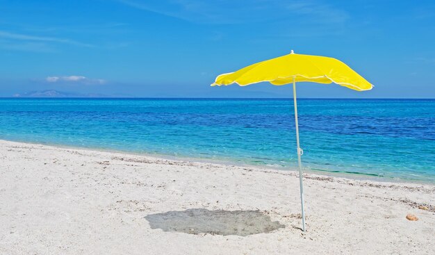 Sombrilla amarilla en una playa desierta