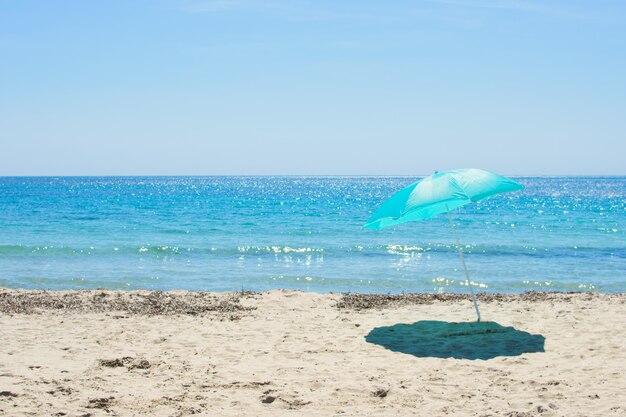 Foto sombrilla azul en la playa de arena contra el mar azul costa blanca de españa y el cielo. concepto de vacaciones.