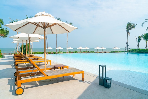 sombrilla con cama piscina alrededor de la piscina con fondo marino - concepto de vacaciones y vacaciones