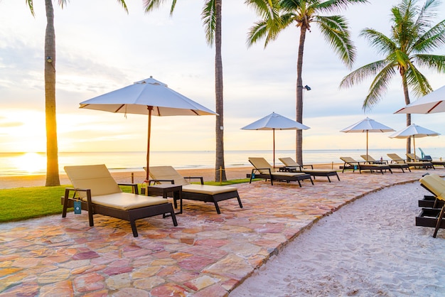 Sombrilla y silla alrededor de la piscina en el hotel resort con amanecer en la mañana - concepto de vacaciones y vacaciones