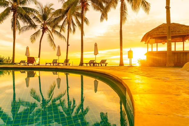 Foto sombrilla y silla alrededor de la piscina en el hotel resort con amanecer en la mañana