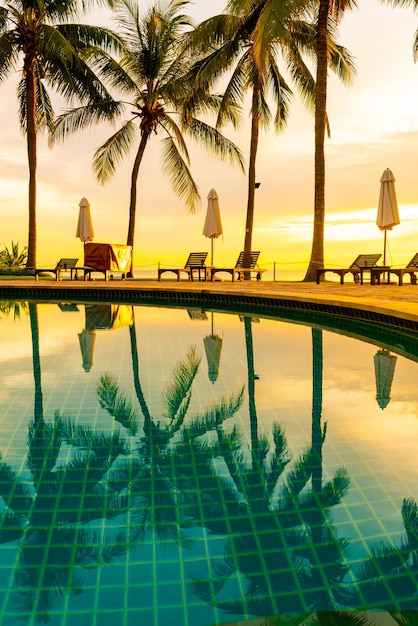 Sombrilla y silla alrededor de la piscina en el hotel resort con amanecer en la mañana