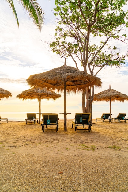 Sombrilla y silla alrededor de la piscina en el hotel resort para viajes de placer y vacaciones cerca de la playa del océano al atardecer o al amanecer.