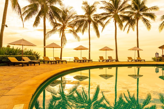 Foto sombrilla y silla alrededor de la piscina en el hotel resort para viajes de placer y vacaciones cerca de la playa del océano del mar