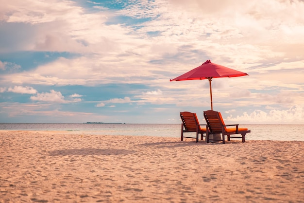 Sombrilla y sillas de pareja en colores de puesta de sol de playa tropical, luz. Fondo abstracto de vacaciones