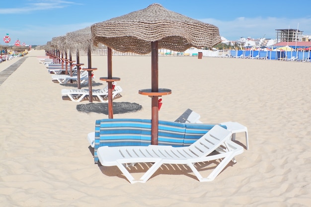 Sombrillas de madera en una fila en una playa soleada. Para el resto.