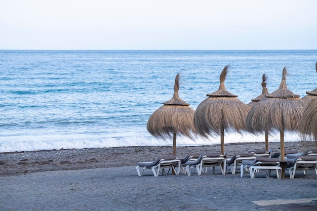 Sombrillas de paja y cómodas tumbonas en la orilla del Mediterráneo