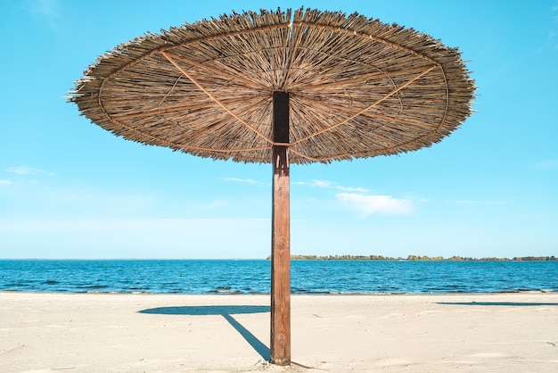 Sombrillas de playa de paja para sombra cerca del río en el fondo del paisaje